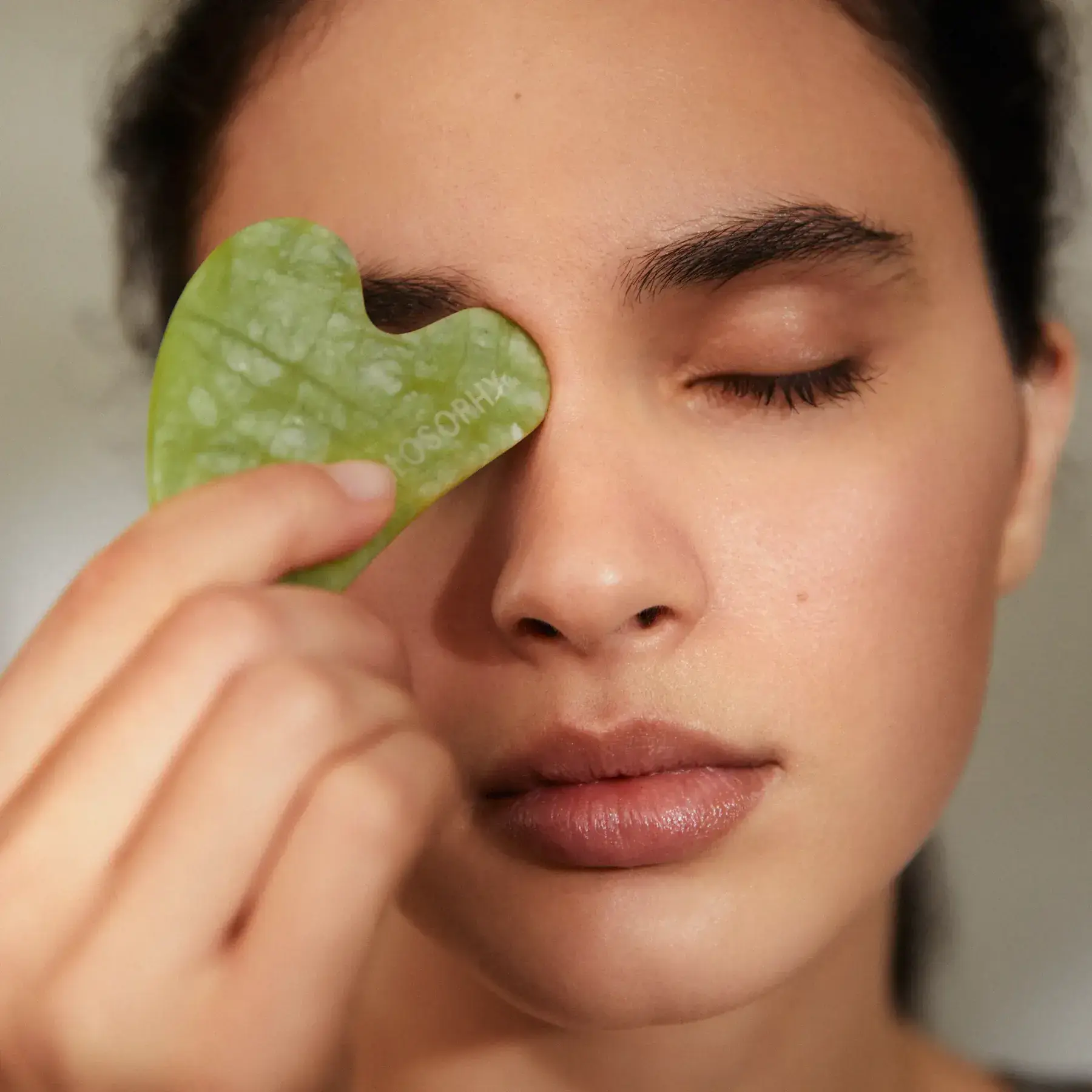 Mujer con una piedra gua sha sobre el ojo